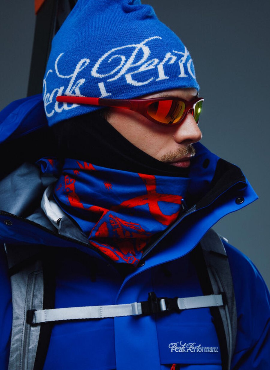 Model met Peak Performance 40Y muts, skibril en blauwe GORE-TEX skijas